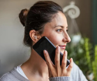 Image of a woman wearing a hearing aid and listening to a mobile phone.