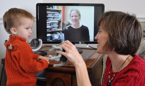 A woman interating with a child in front of a video display.